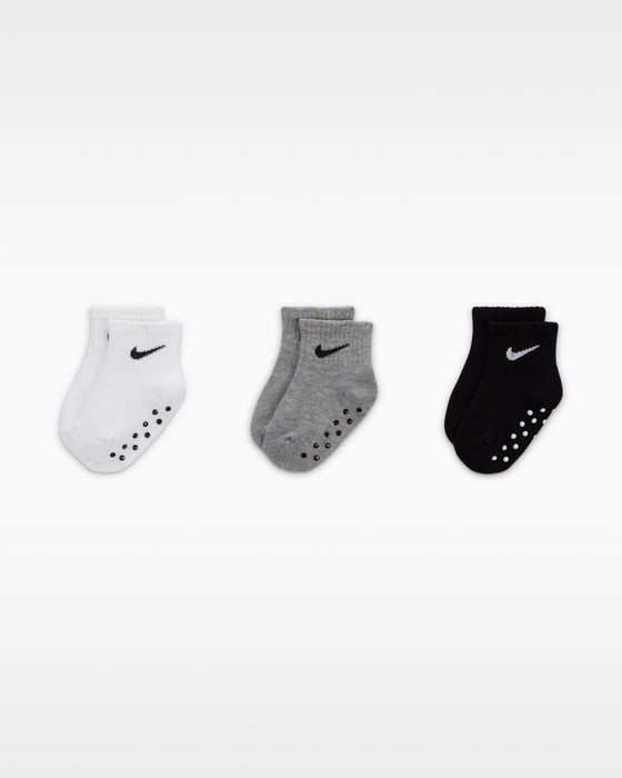Nike baby gripper socks in white, grey, and black displayed side by side on a plain background.