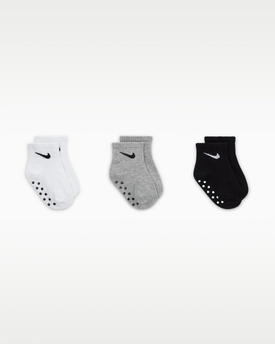 Nike baby gripper socks in white, grey, and black shown in a row on a plain background.