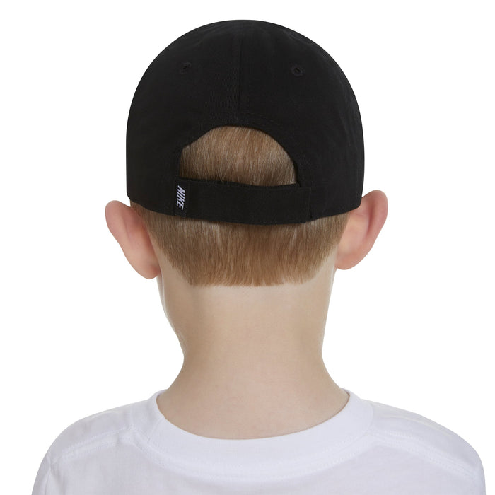 Nike kids’ black cap shown on a child, rear view highlighting adjustable strap and logo detail.