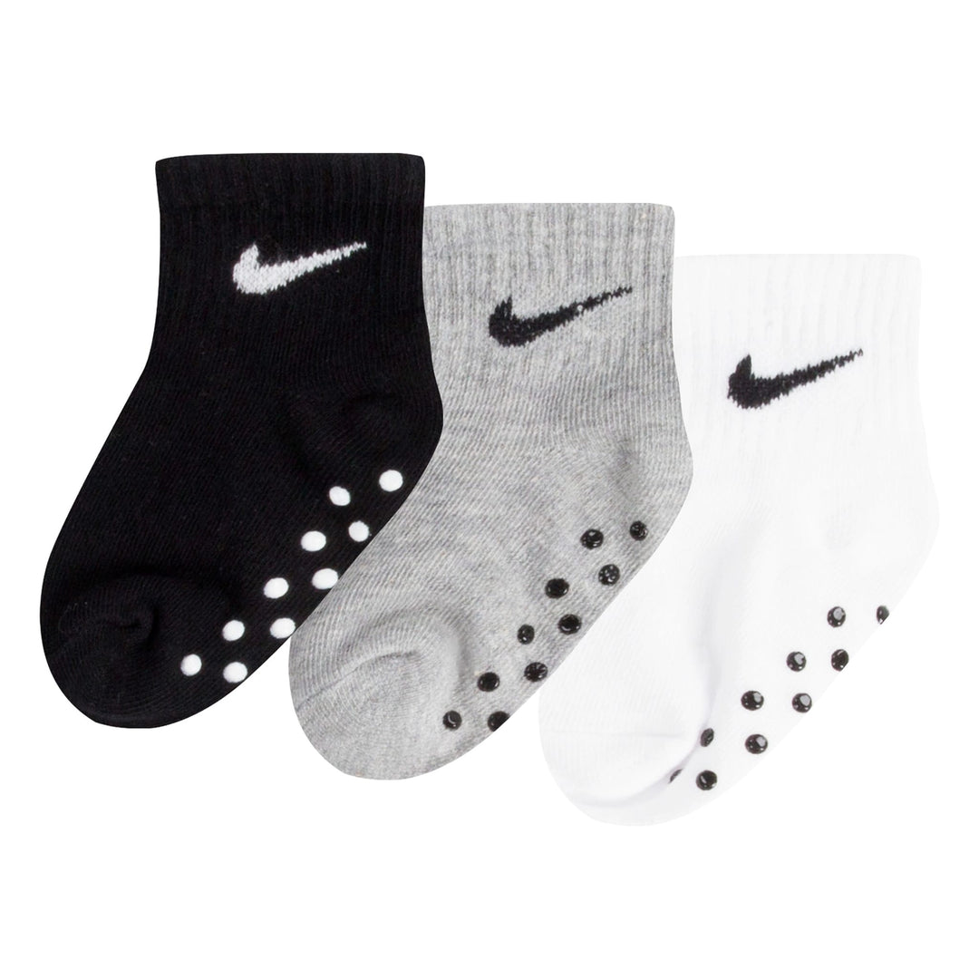 Nike baby grip socks in black, grey, and white colors displayed side by side on a white background.