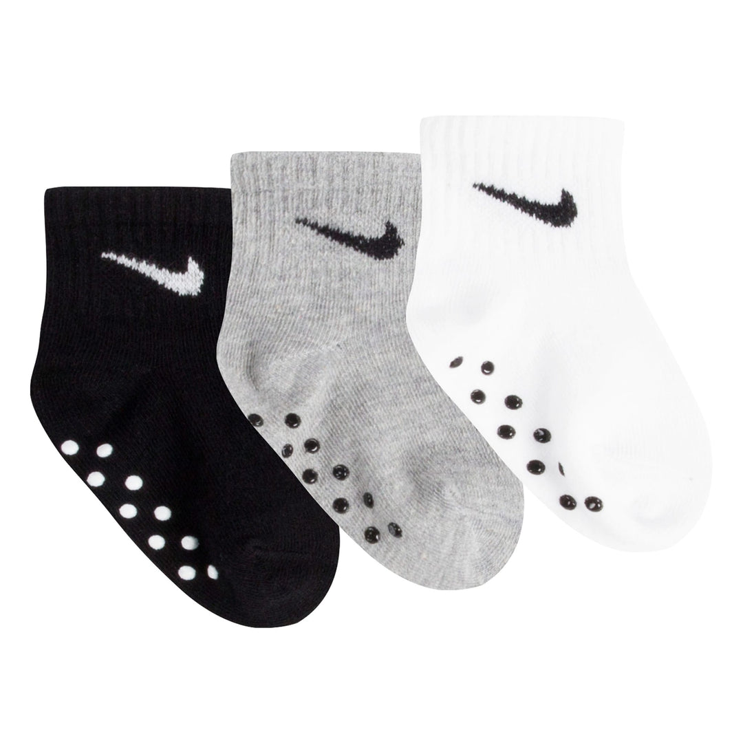 Nike baby grip socks set in black, grey, and white, shown flat with non-slip soles visible.