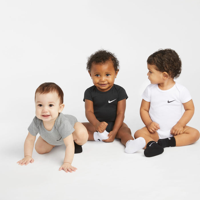 Nike baby bodysuits modeled by three babies sitting and crawling on a white backdrop.