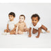 Nike baby bodysuits in beige, tan, and white, shown on three babies against a white background.