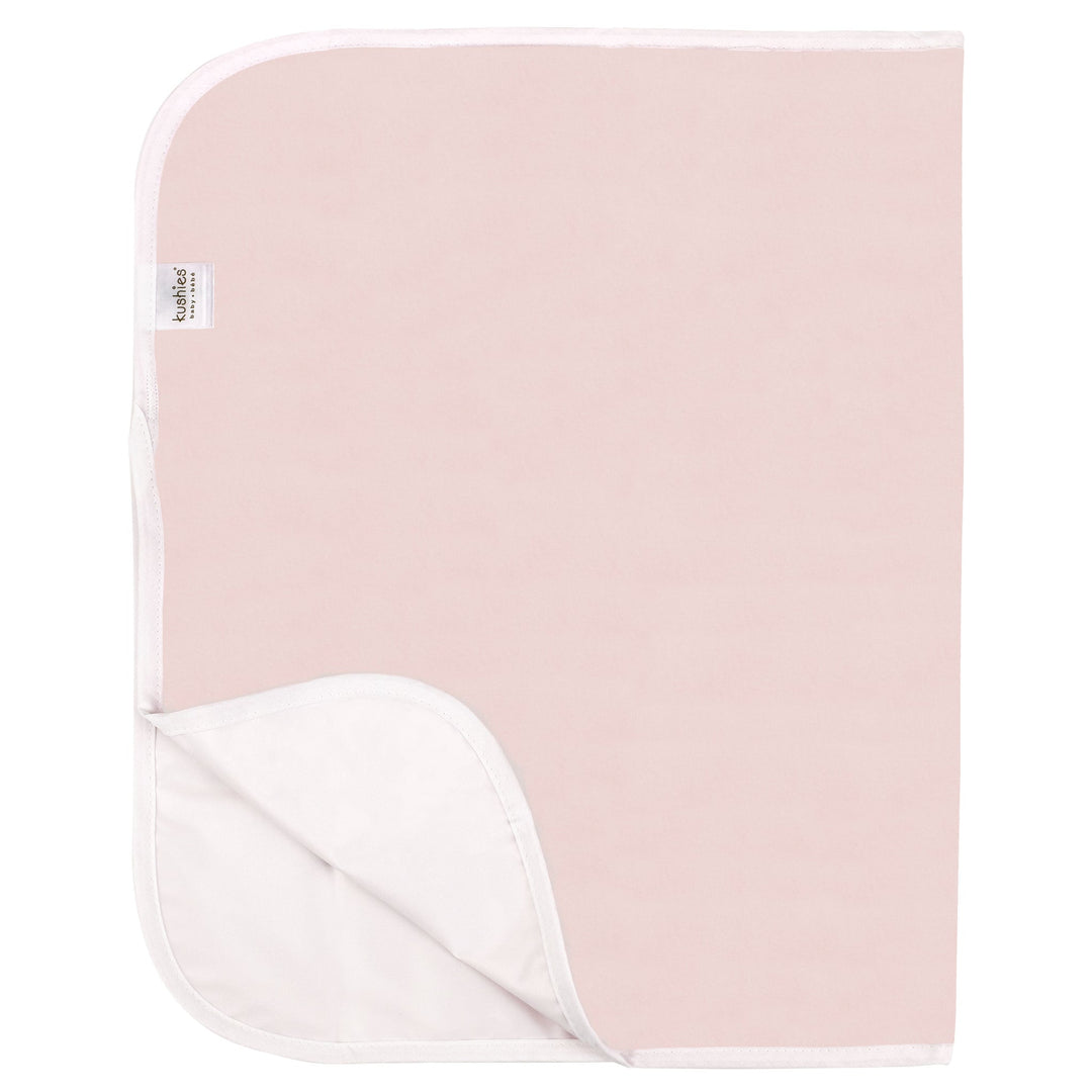 Light pink waterproof baby changing pad with white trim on plain background