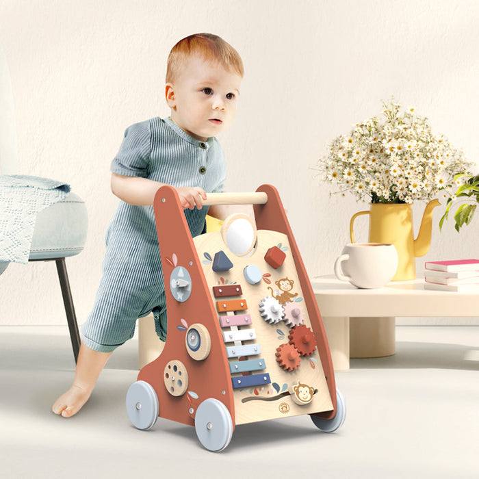 Wooden multi-activity push toy shown with a toddler walking indoors near a table with flowers.