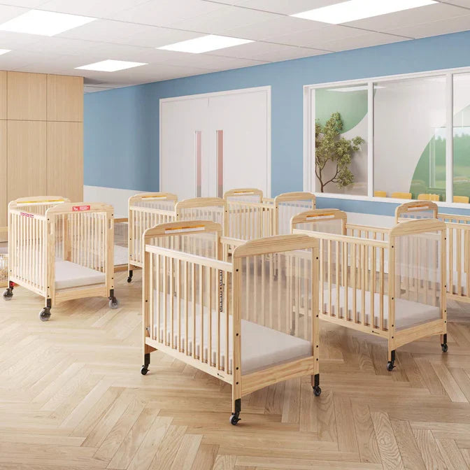 Clearview wooden cribs with wheels arranged in a bright daycare room with blue walls