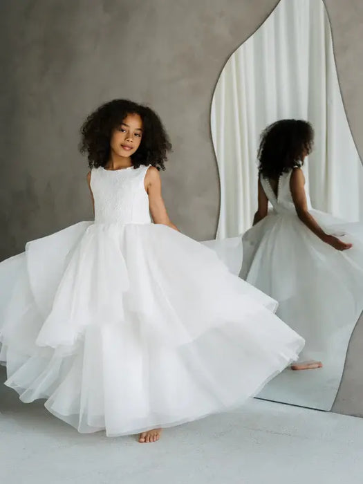 Sunny JK07 Pearl Back Horsehair Communion Dress shown on a young girl twirling beside a mirror.