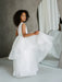 Sunny JK07 Pearl Back Horsehair Communion Dress shown on a smiling girl standing beside a mirror.