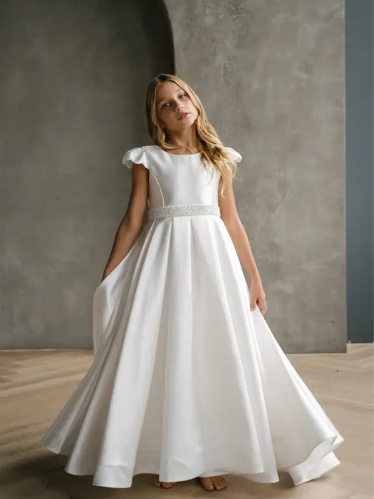 Teter Warm Charlotte satin communion dress shown on a young girl in a minimalist studio setting.