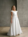 Teter Warm Charlotte satin communion dress shown on a girl standing in a minimalist indoor setting.