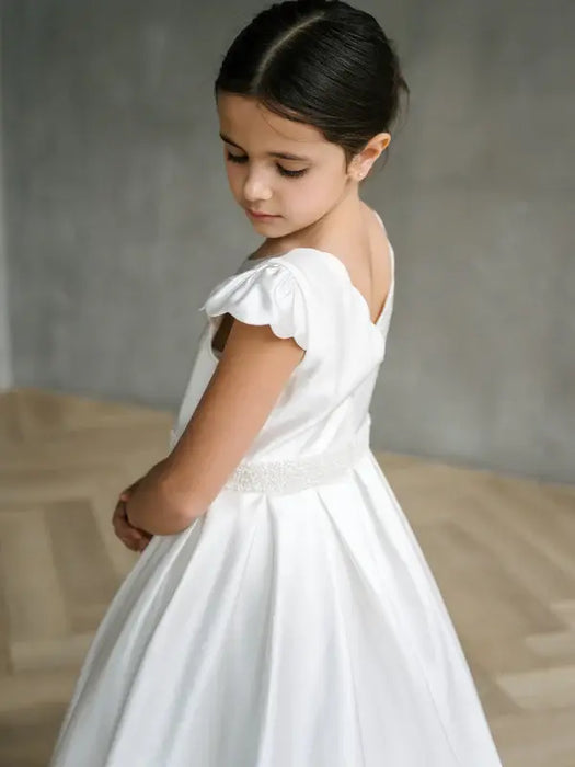Teter Warm Charlotte satin communion dress on a young girl standing indoors, facing away.