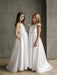 Charlotte satin communion dress shown on two girls standing indoors against a plain gray wall.