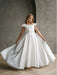 Teter Warm Charlotte satin communion dress displayed on a girl standing indoors against a gray wall.