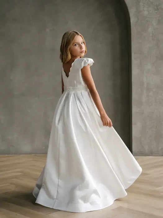 Teter Warm Charlotte satin communion dress shown on a young girl posing in a neutral studio setting.