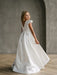Teter Warm Charlotte satin communion dress shown on a young girl posing in a neutral studio setting.