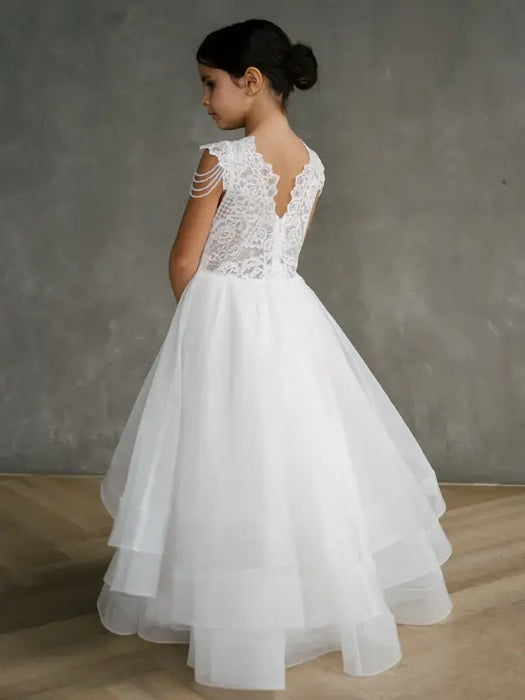 Teter Warm Lorelai Pearl Communion Dress shown on a girl standing indoors with lace and tulle details.