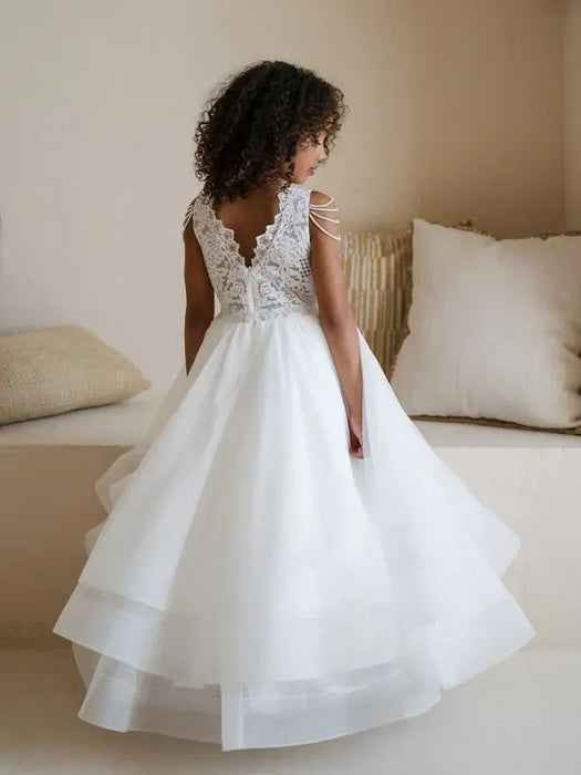 Teter Warm Lorelai Pearl Communion Dress shown on a young girl with lace back in a cozy room.
