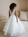 Teter Warm Lorelai Pearl Communion Dress shown on a young girl with lace back in a cozy room.