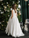 Teter warm off-white communion dress shown on a girl standing by a decorated Christmas tree.