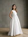 Teter warm off white communion dress worn by a girl standing indoors against a grey wall.