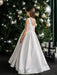 Teter warm off white communion dress with pearl back shown on a girl standing near a decorated Christmas tree.