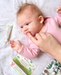 Jack N' Jill Teething Gel applied to a baby's gums while lying on a patterned crib sheet.