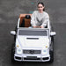 Mercedes-Maybach G 650 kids ride-on car in white driven outdoors by a young woman on pavement.