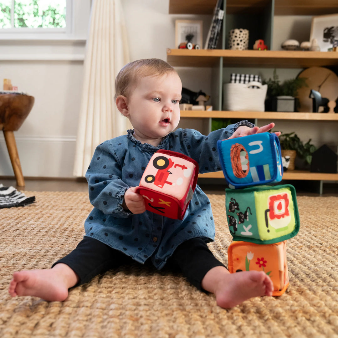 b.box Alpha Skating Soft Blocks sensory toy stacked by a baby on a carpeted floor