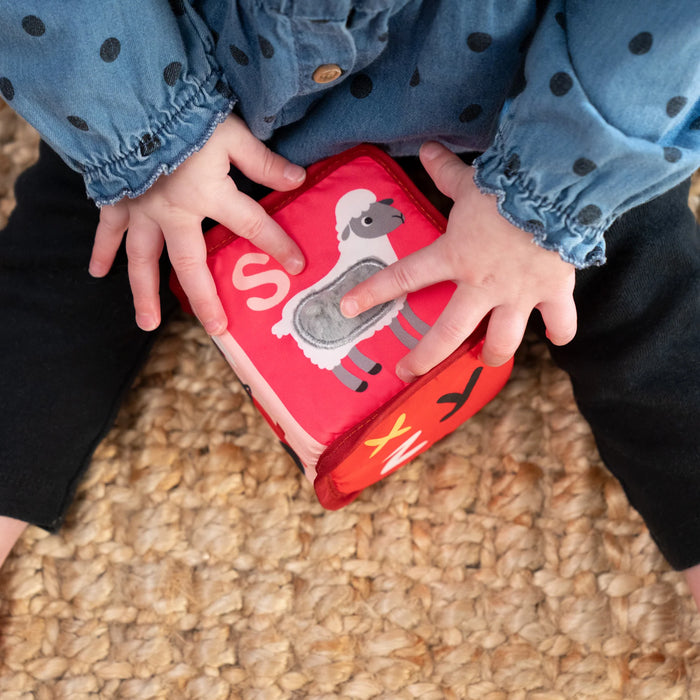 b.box alpha skating soft blocks sensory toy being played with by a child on a woven rug