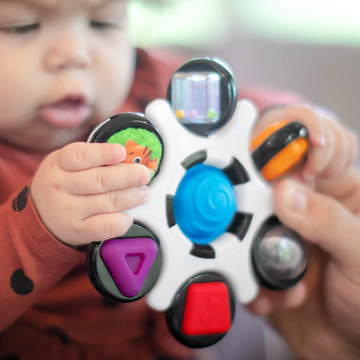b.box baby sensory toy clutch held by a baby, colorful interactive features visible