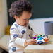 b.box baby sensory toy clutch held by a baby on a wooden table indoors