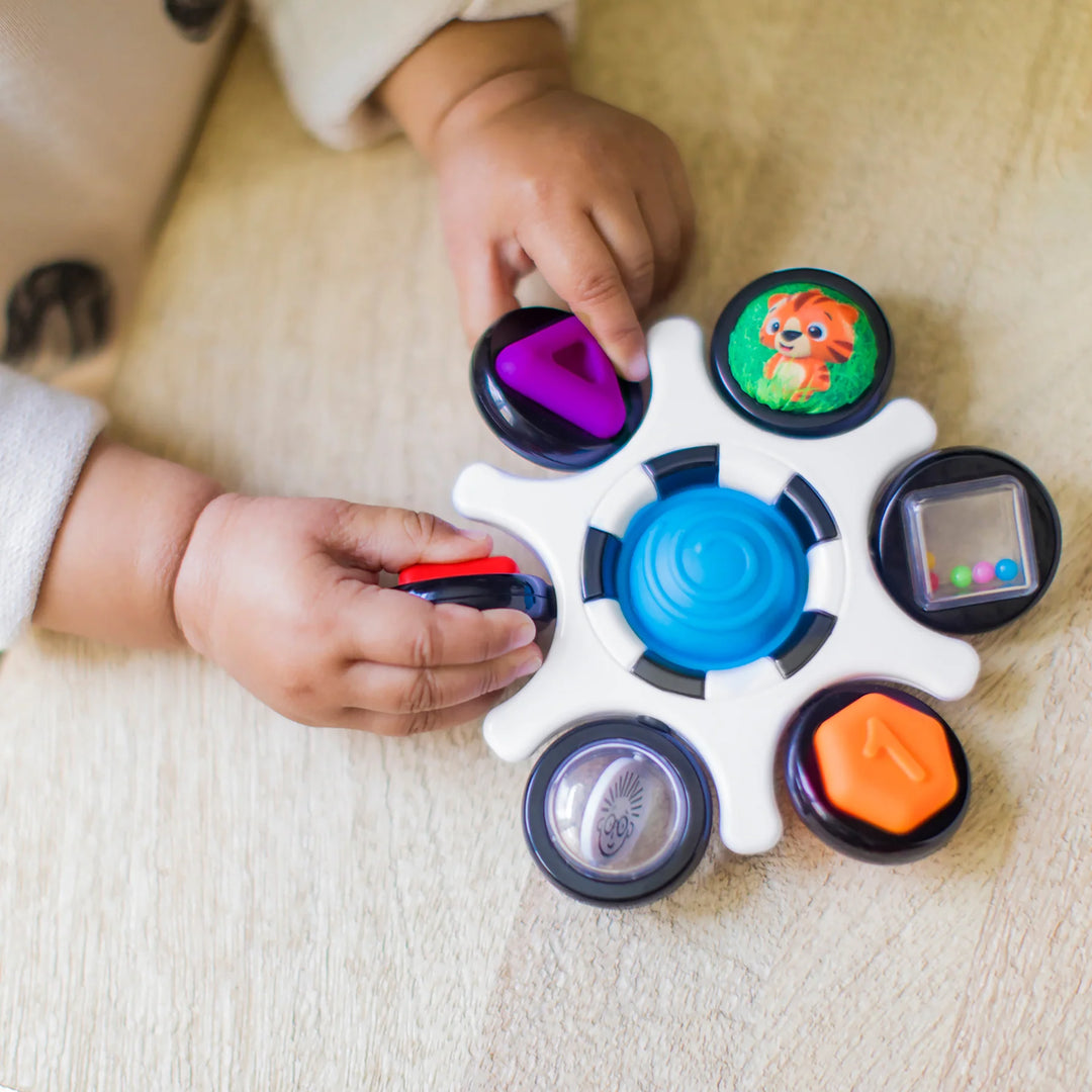 b.box baby sensory toy clutch being explored by a baby on a wooden surface