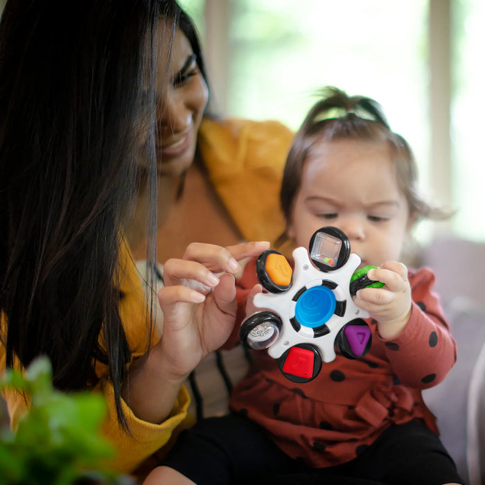 b.box baby sensory toy clutch being held and explored by a baby and adult indoors