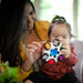 b.box baby sensory toy clutch being held and explored by a baby and adult indoors