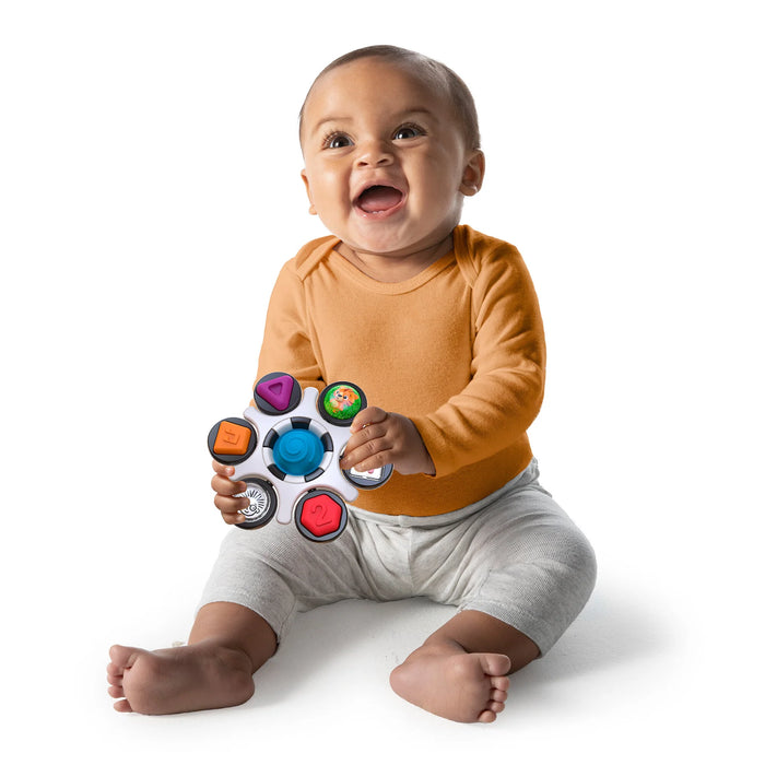 b.box baby sensory toy clutch held by a smiling baby sitting on the floor