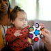 b.box baby sensory toy clutch held out to an infant sitting with an adult on a couch