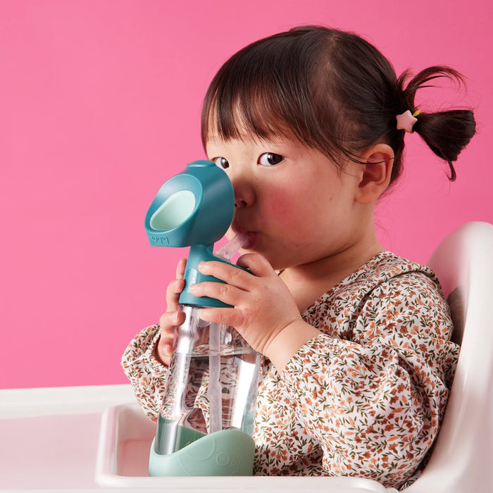 b.box kids tritan drink bottle held by a toddler in a high chair against a pink background.