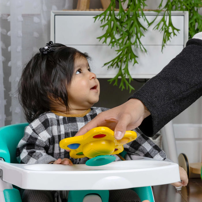 b.box Pop & Glow Starfish sensory toy placed on a highchair tray in front of a smiling baby