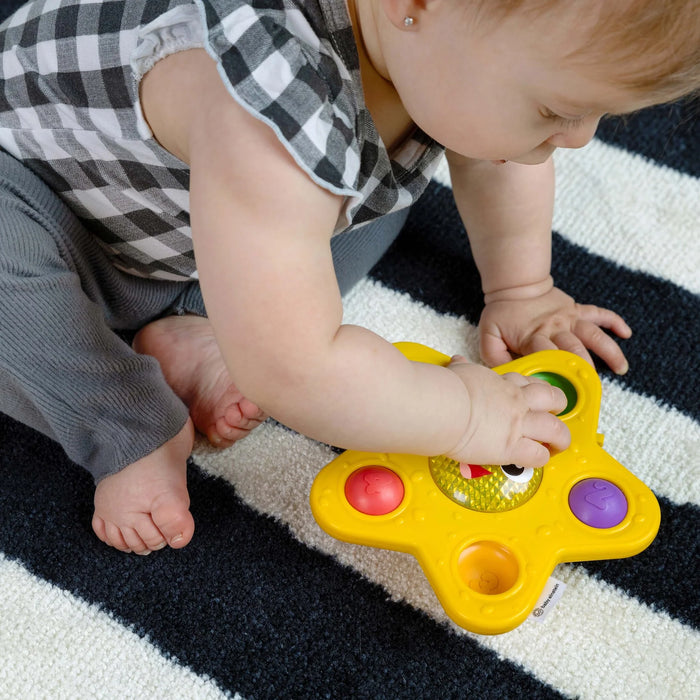 b.box pop & glow starfish sensory toy in use by a baby sitting on a striped carpet