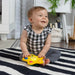 b.box Pop & Glow Starfish Sensory Toy in use by a smiling baby sitting on a striped rug indoors.