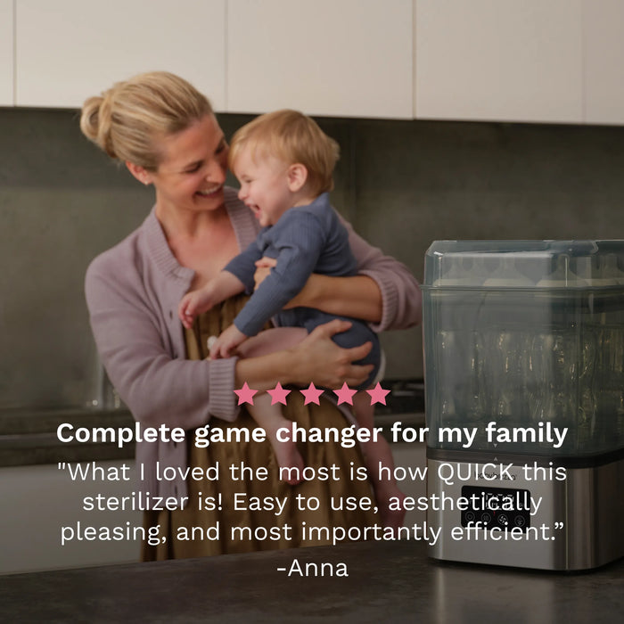 Baby Brezza Super Fast Sterilizer and Dryer on a kitchen counter beside a smiling woman holding a baby.