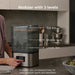 Baby Brezza Super Fast Sterilizer and Dryer on a kitchen countertop with a person using the control panel.