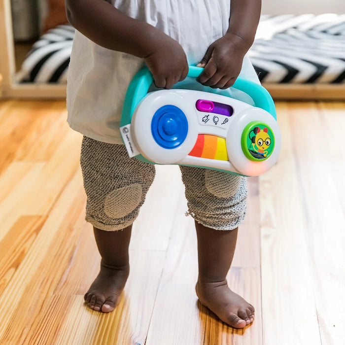 Baby Einstein Toddler Jams musical toy held by a child standing on a wooden floor.