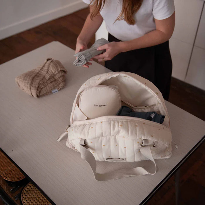 Baby on Board doudoune cotton diaper bag open on a table, being packed by a woman in a white shirt.