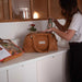 Baby On Board Doudoune diaper bag on a kitchen counter, with a person placing a bottle inside.