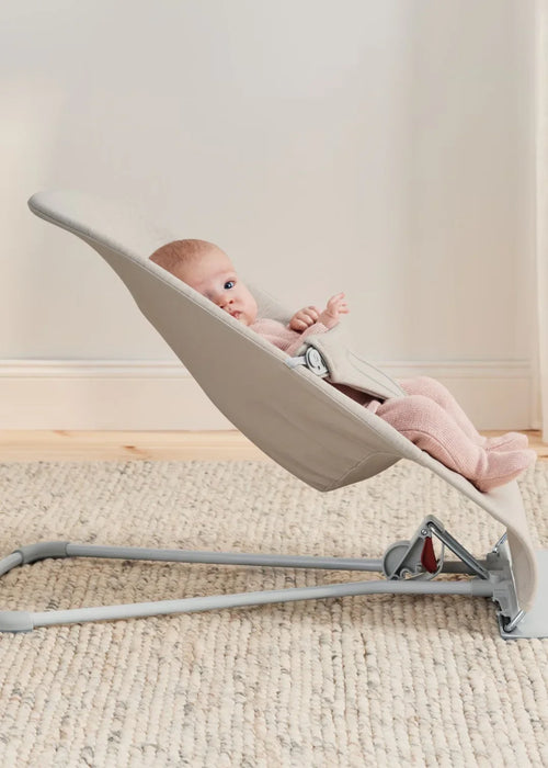 BabyBjorn Bouncer Bliss 3D Mesh in light beige with a baby lying comfortably on a carpeted floor.