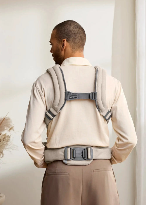 BabyBjorn Harmony Baby Carrier beige shown on man from behind indoors