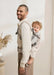 BabyBjorn Harmony baby carrier in beige worn by an adult carrying a child on their back indoors.