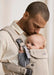 BabyBjörn Harmony baby carrier in beige with a baby held close by an adult indoors