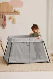 BabyBjorn Play Yard Light in silver with a toddler standing inside in a cozy nursery setting.